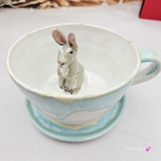 Filiżanka ZAJĄC ceramiczna ze spodkiem z ZAJĄCEM szarakiem w środku ręcznie toczona i malowana w kolorze białym i błękitnym oraz szary zając kubek zając z zającem szarakiem filiżanka na Wielkanoc
