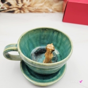 Filiżanka SURYKATKA ze spodkiem ceramiczna z uroczą SURKĄ w środku ręcznie toczona i malowana odcienie zieleni i niebieskiego kubek na prezent dla miłośnika natury piękna filiżanka w odcieniach zieleni turkusowe jeziorko surykatka