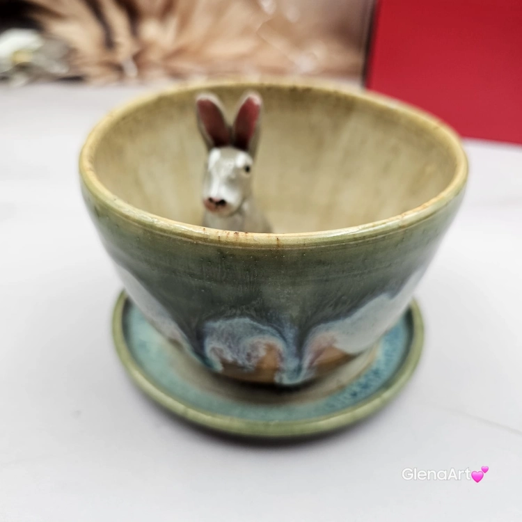 Filiżanka ZAJĄC ceramiczna ze spodkiem z ZAJĄCEM szarakiem w środku ręcznie toczona i malowana w kolorach zielonych niebieskich brązach i beżach oraz szary zając kubek zając z zającem szarakiem filiżanka na Wielkanoc i nie tylko