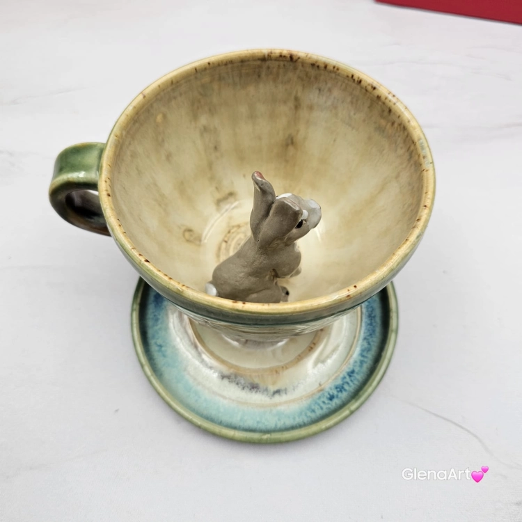Filiżanka ZAJĄC ceramiczna ze spodkiem z ZAJĄCEM szarakiem w środku ręcznie toczona i malowana w kolorach zielonych niebieskich brązach i beżach oraz szary zając kubek zając z zającem szarakiem filiżanka na Wielkanoc i nie tylko
