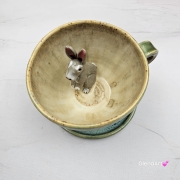 Filiżanka ZAJĄC ceramiczna ze spodkiem z ZAJĄCEM szarakiem w środku ręcznie toczona i malowana w kolorach zielonych niebieskich brązach i beżach oraz szary zając kubek zając z zającem szarakiem filiżanka na Wielkanoc i nie tylko