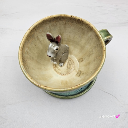 Filiżanka ZAJĄC ceramiczna ze spodkiem z ZAJĄCEM szarakiem w środku ręcznie toczona i malowana w kolorach zielonych niebieskich brązach i beżach oraz szary zając kubek zając z zającem szarakiem filiżanka na Wielkanoc i nie tylko